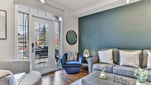 Un salón moderno con un sofá gris, un sillón azul y una mesa de centro con un adorno.
