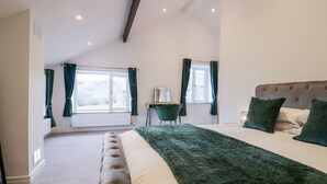 Ein Schlafzimmer mit einem großen Bett, einem Schreibtisch und Blick ins Freie.