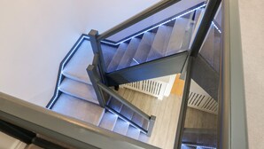 Ein Blick auf eine moderne Treppe mit geometrischem Geländer und LED-Beleuchtung entlang der Stufen.