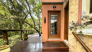 A wooden deck leading to a building with a glass door and a small porch area. - Casa Alto Padrão na Granja Viana - Cond. Fechado (Carapicuiba)