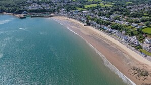 An aerial view of a coastal town with a sandy beach, residential buildings, and a marina. - Glenvale - 2 Bedroom Apartment - Saundersfoot (Saundersfoot)