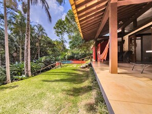 Un espacio exterior moderno con piscina, sillas de descanso y una hamaca.
