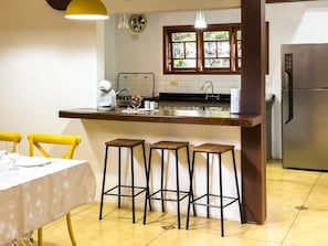 Uma cozinha compacta com área de refeições, cafeteira e geladeira.