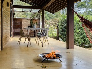 Une terrasse extérieure avec un foyer, une table et des chaises, et un hamac.
