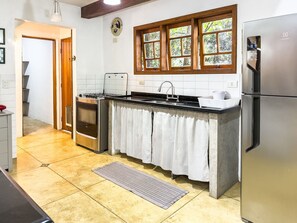 Una cocina equipada con estufa a gas, horno, pileta y refrigerador.