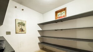 Une pièce aux murs blancs, une petite fenêtre donnant sur un paysage et un tableau représentant un arbre.