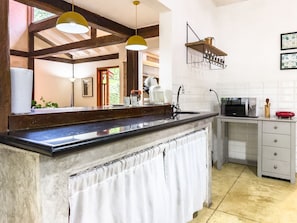 Une cuisine dotée d’un plan de travail en marbre, d’un évier, d’un four à micro-ondes et d’un luminaire suspendu.