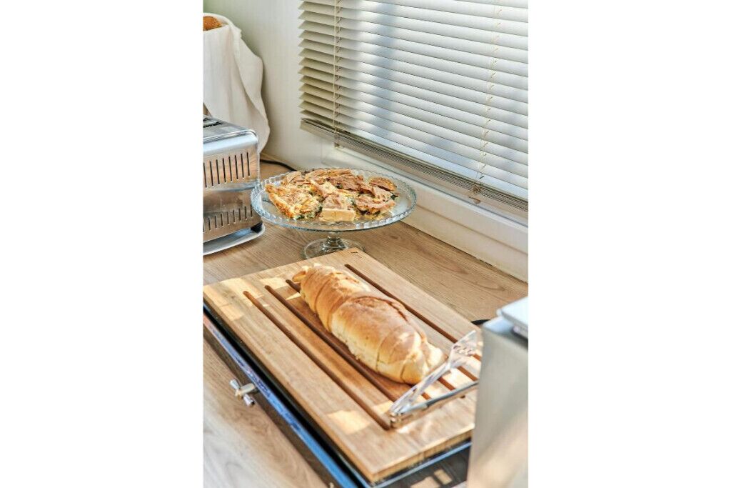 A kitchen counter with a loaf of bread, a glass dish with food, and a toaster.