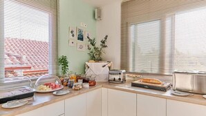 Keittiössä on leivänpaahdin, leipäteline ja erilaisia elintarvikkeita työtasolla.