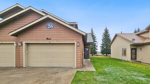 A residential building with a garage, a number '26' sign, and a well-maintained lawn.