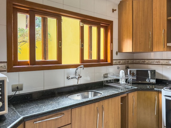 Una cocina con armarios de madera, un lavamanos de acero inoxidable, un microondas y un tostador.