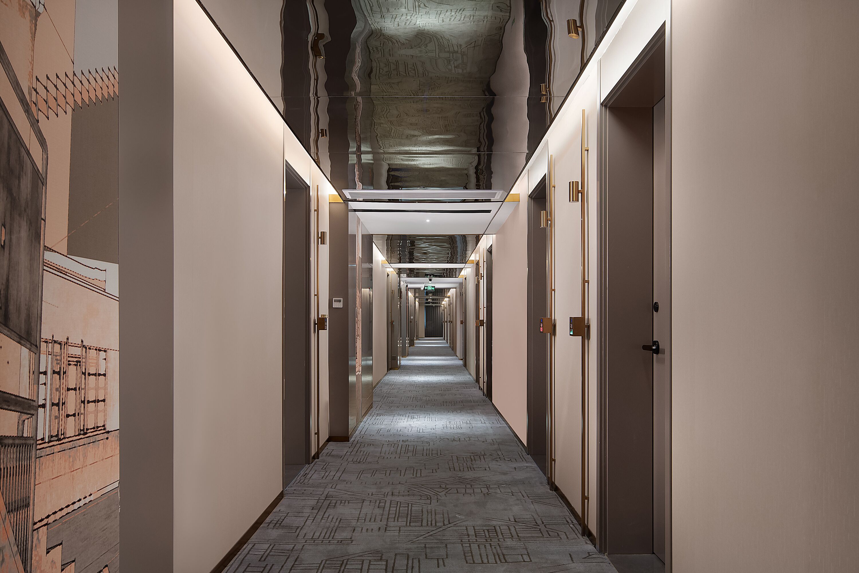 A long, narrow hallway with doors on both sides, a patterned floor, and a ceiling with a unique design.