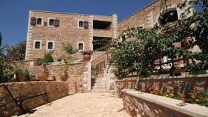 A stone building with multiple windows, a staircase leading to a higher level, and potted plants.