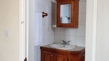 A bathroom with a wooden vanity, a mirror, and a white sink.