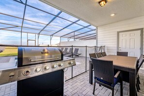 Una terrazza esterna con una griglia, mobili in vimini e vista sul cielo attraverso un soffitto in vetro.