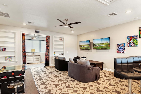 Enjoy gaming and entertainment in this vibrant game room with dual TVs and arcade fun.