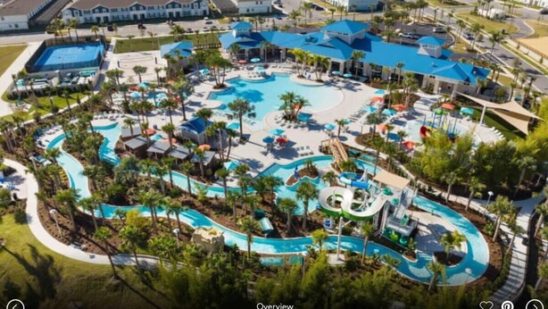 Ein Luftbild eines Resorts mit großem Poolbereich, mehreren Wasserrutschen und umgebenden Gebäuden.