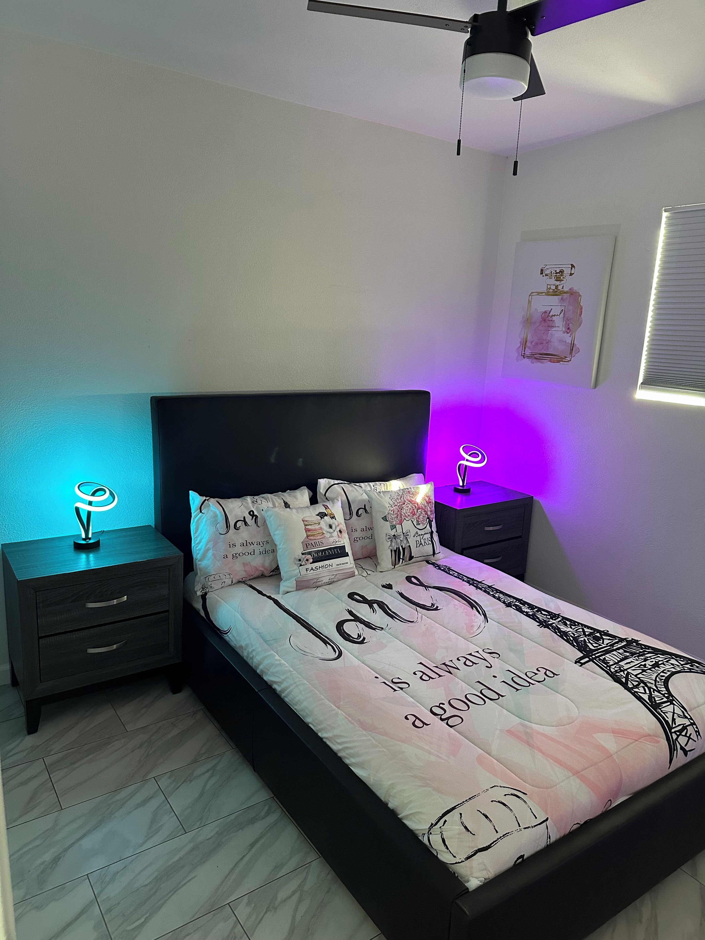 A bedroom with a bed, two bedside tables, a ceiling fan, and a wall-mounted picture.