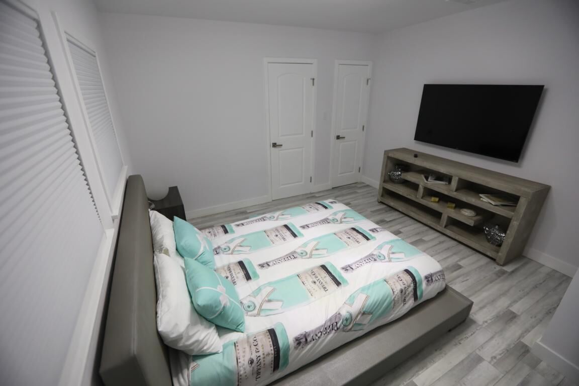 Une chambre à coucher avec un lit, un téléviseur fixé au mur et une armoire en bois.