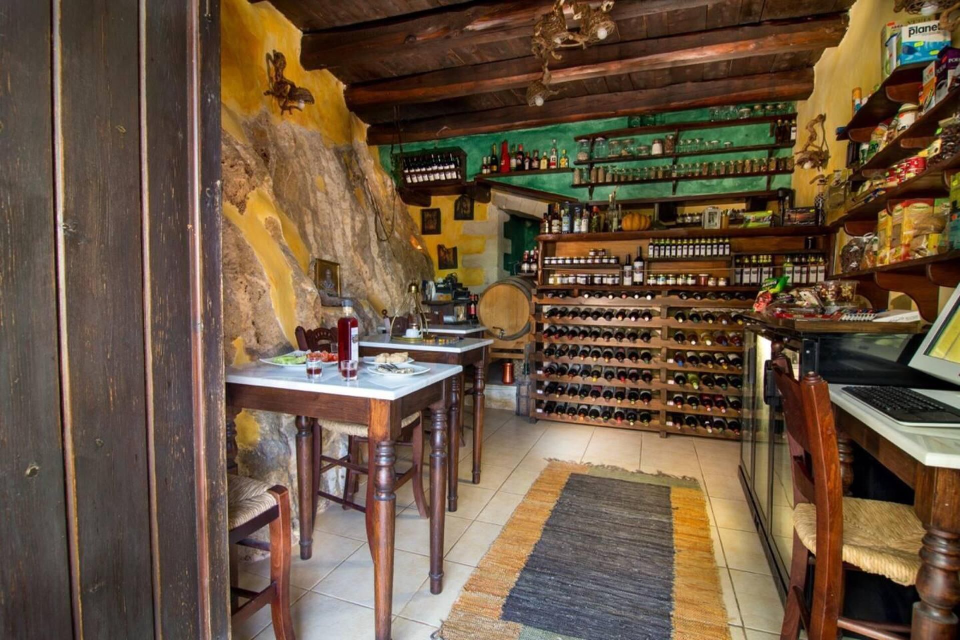 A rustic interior with wooden furniture, a wine rack, and shelves stocked with various items.