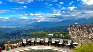 Un espace extérieur aménagé avec des murs et des tables en pierre, offrant une vue sur un paysage montagneux.