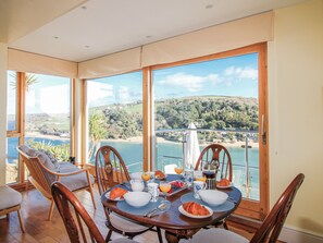 Un coin repas avec une table mise pour le petit-déjeuner, offrant une vue panoramique sur un lac et des collines.