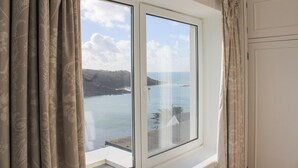 A room with a large window offering a view of the sea and cliffs. - 2 Channel View (Salcombe)