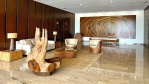 A modern lobby with a wooden reception desk, seating area, and a large abstract wall art piece. - APARTMENT  BETWEEN OCEAN AND RAIN FOREST - Beachside apartment with outdoor pool (Panama City)