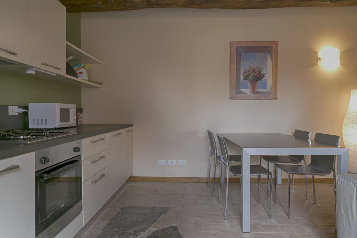 A compact kitchen with a microwave, oven, and a dining table with chairs.