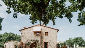 A stone building with a covered entrance, outdoor seating, and potted plants.