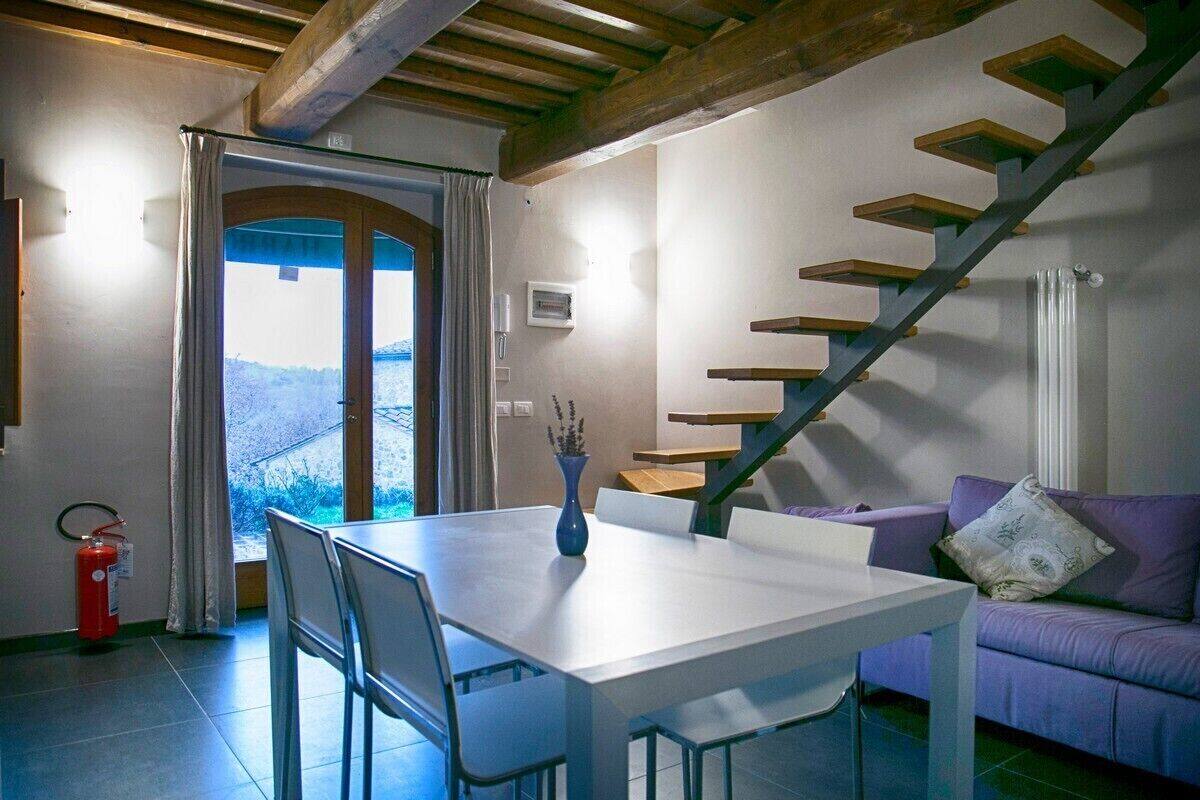 A dining area with a table and chairs, a purple sofa, a staircase, and a view of the outdoors.