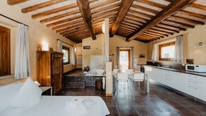 A spacious room with a large bed, a kitchenette, a bathroom, and a dining area.