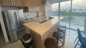 Una cocina moderna con un refrigerador de acero inoxidable, un lavamanos y una isla grande con taburetes de bar.