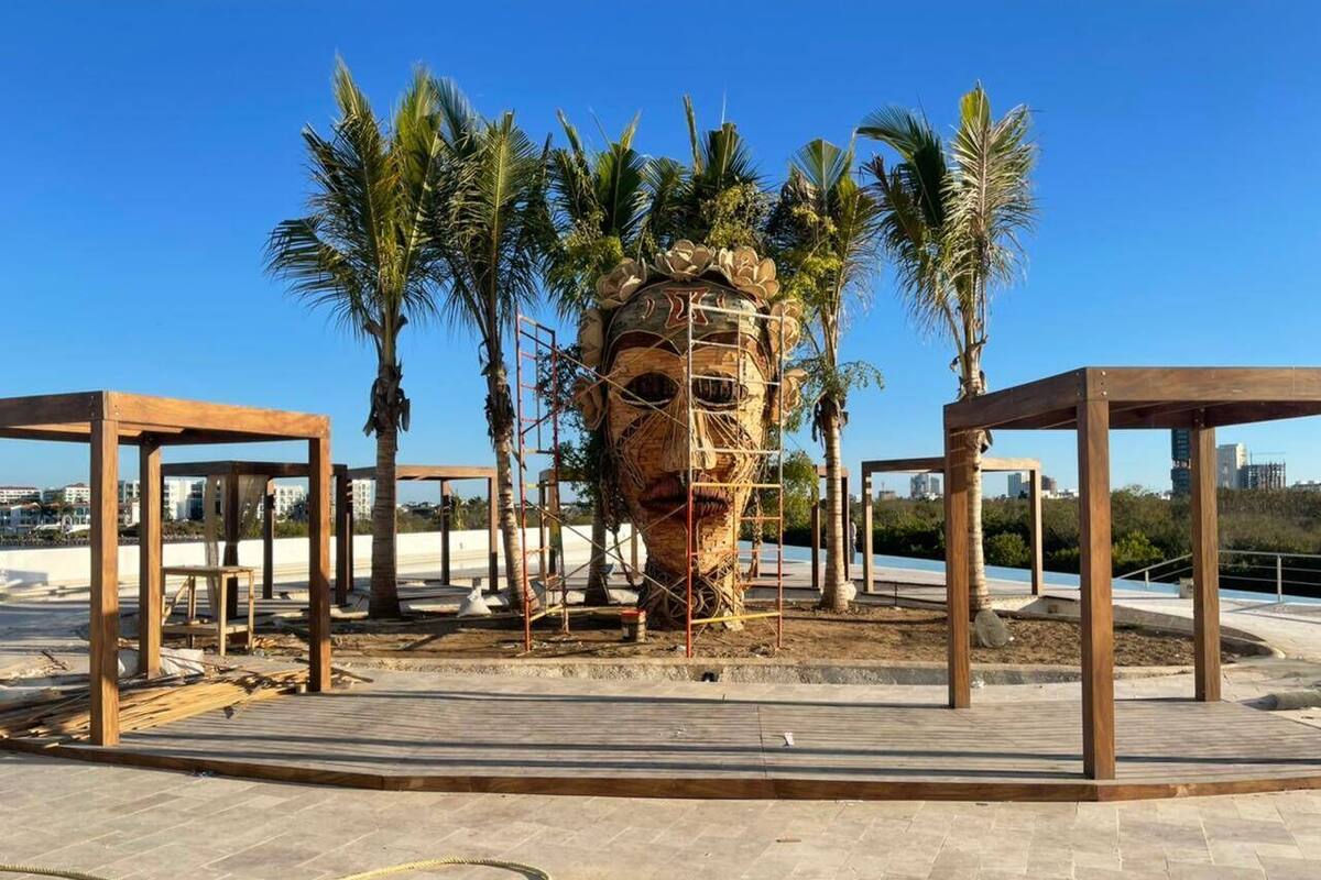 An outdoor area with a central structure surrounded by palm trees and wooden frameworks.