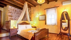 Une chambre à coucher avec un lit en bois, une table de chevet, une commode, un miroir et un mur en pierre.