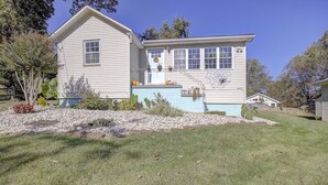 A two-story house with a front porch, a small garden, and a clear blue sky. - Cottage on the Bay (Saint Leonard)