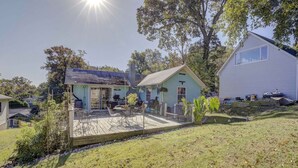 A two-story house with a patio area, a small garden, and a large tree in the background. - Cottage on the Bay (Saint Leonard)