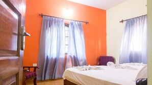 Una habitación con una cama, una puerta de madera y paredes anaranjadas.
