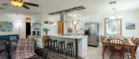 A modern kitchen with a central island, bar stools, and a dining table with chairs.