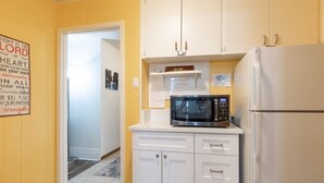 Una cocina compacta con muebles blancos, un microondas y un refrigerador.