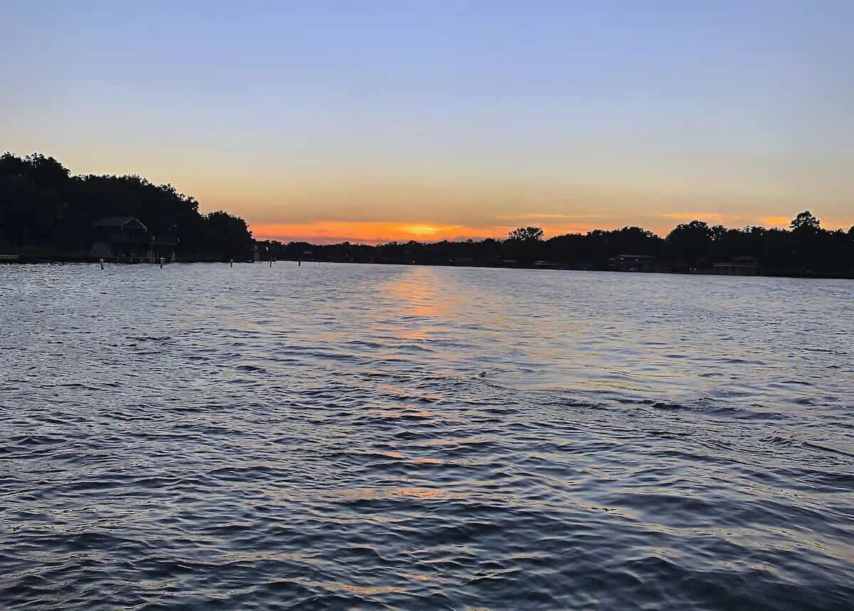 A calm lake at sunset with a distant shoreline.