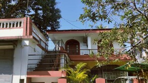A two-story building with a red roof, a staircase leading to the upper floor, and a gated entrance.