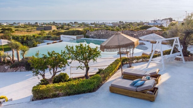 Zona de piscina con sillas de descanso y vista al mar.