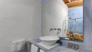 Un baño moderno con un espejo grande, un lavamanos blanco y una ducha.
