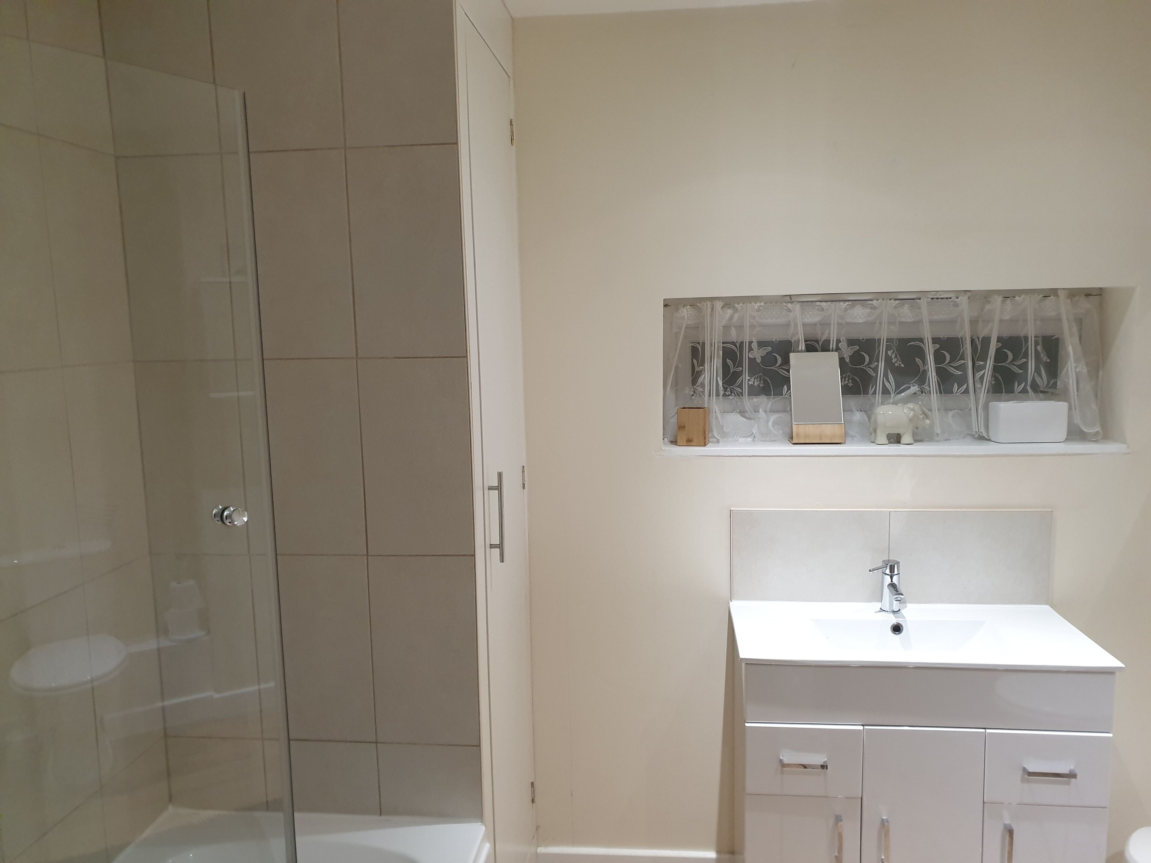 A bathroom with a glass shower enclosure, a white sink, and a mirror above the sink.