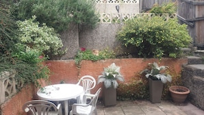 A patio with a round table and four chairs, surrounded by potted plants and a decorative fence. - House - Sleeps 5 - Pets Ok - Parking - Garden (Bristol)