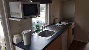 A compact kitchen with a microwave, sink, and a window providing a view of the street.