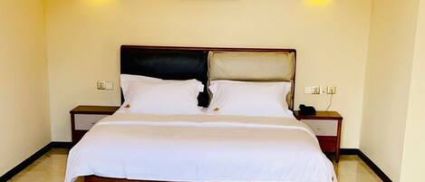 Une chambre d’hôtel comprenant un lit, des tables de chevet, une table ronde et deux chaises.