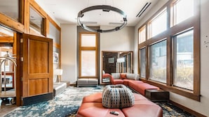 A spacious room with a large window, a circular ceiling light, a sofa, and a remote control on the floor. - Sundial B404 | Ski-in/Ski-out | Mountain Views | Full Kitchen | Pools & Hot Tubs (Park City)