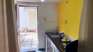 A kitchen with a yellow wall, a sink, and a window. - Alexmarie Holiday Home  (5) nr Candolim Beach  (Bardez Candolim)
